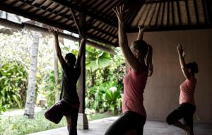 a group of three women performing aorative yoga exercise at Lotus Bungalows in Candidasa