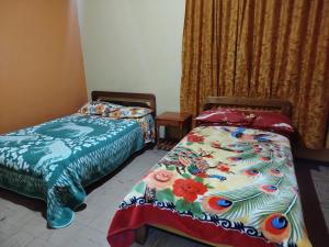 a bedroom with two beds and a bedspread with flowers at Hotel atahualpa in Pasto