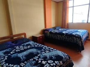 a bedroom with two beds with blue comforters on them at Hotel atahualpa in Pasto