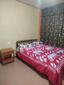 a bedroom with a bed with a red comforter and a table at Hotel atahualpa in Pasto