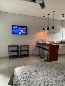 a bedroom with a desk and a kitchen with a tv on the wall at Lua Nova Studio II in Caraguatatuba