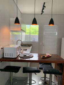 a kitchen with a counter with a microwave and stools at Lua Nova Studio II in Caraguatatuba +7 photos