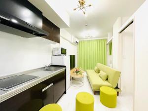 a kitchen with a couch and some yellow stools at The Grand Win in Fukuoka