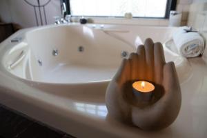 a hand holding a candle in front of a bath tub at A Heavenly Escape in Halls Gap
