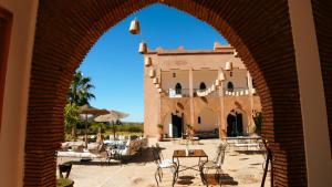 an archway leading to a building with tables and chairs at Kasbah Caracalla in Aghmat