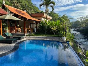 a swimming pool in front of a house with a river at Uma Swari Villa Sidemen in Sidemen