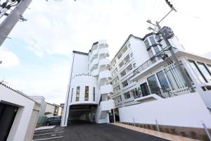 a white apartment building with a parking lot at The Grand Win in Fukuoka