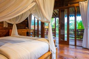 a bedroom with a bed with curtains and a balcony at Umah Jati Villa in Gianyar +90 photos