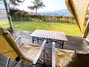 a wooden deck with chairs and a table and a picnic table at Wando Haegeum Pension in Wando
