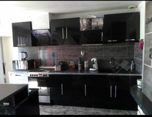 a kitchen with black cabinets and a stove at Chambre double avec lit clic clac in Saint-Pardoux-Isaac