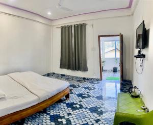 a bedroom with a bed and a tv on a wall at Juihal Residency & Kitchen in Kāziranga