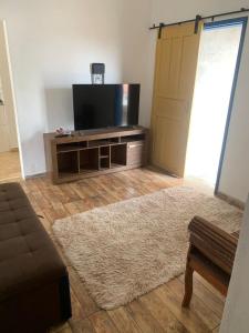 a living room with a flat screen tv and a couch at Casa vila carolla in Tiradentes