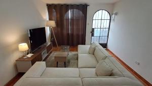 a living room with a white couch and a tv at Modern Apartament Pool & Jacuzzi 2 room in Lima