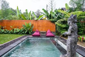 a fountain in a garden with a statue and pink pillows at Umah Jati Villa in Gianyar