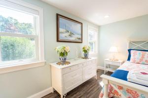 a bedroom with a bed and two vases with flowers on a dresser at Cape Seacret in South Yarmouth