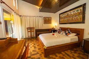 a bedroom with a bed and a desk and a piano at Sajjana House Bali By Magno in Nusa Dua +24 photos