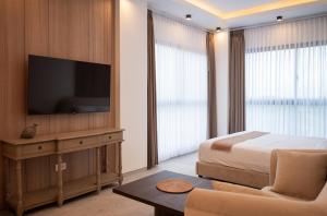 a bedroom with a bed and a flat screen tv at Villa Nuansa in Mantaak