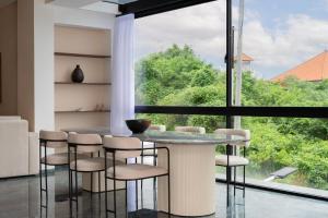 a dining room with a table and chairs and a large window at Villa Nuansa in Mantaak