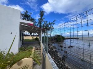 a fence with a view of the ocean at Ashan Laksh Bungalow in Grande Rivière Sud Est +8 photos