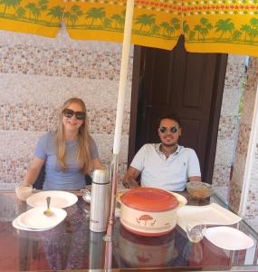 a man and woman sitting at a table under an umbrella at Penuel marari homesty in Mararikulam