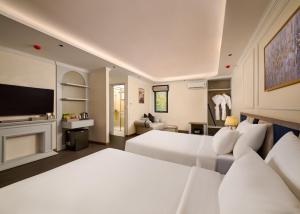 a white bedroom with two beds and a tv at Narci Resort Tam Coc in Ninh Binh