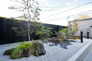 a garden with rocks and plants in front of a fence at 花月hanatsuki in Kyoto