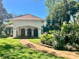 a small white house with a pathway in a yard at Van Kouwenhoven Hostel in Diriamba