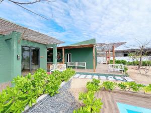 a green house with two white chairs and a pool at Emerald Beach Homestay in Bình Sum