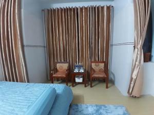 a bedroom with a bed and two chairs and a table at LUNA House in Hue