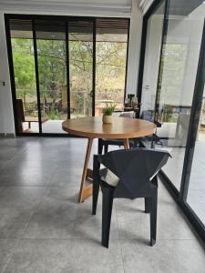 a wooden table and a chair in a room with windows at Mystica in Playa Avellana