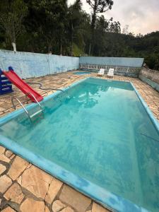 a swimming pool with a red reclining chair in a blue swimming pool at Chácara sol nascente in Suzano
