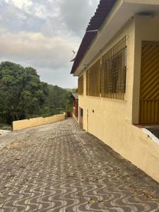 a house with a cobblestone street next to a building at Chácara sol nascente in Suzano