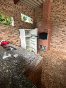 a kitchen with a refrigerator and a brick wall at Chácara sol nascente in Suzano
