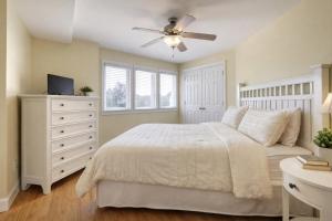 a bedroom with a white bed and a ceiling fan at Captains Watch in Tybee Island