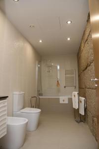 a bathroom with a toilet and a tub and a sink at Hotel Rural Quinta das Quintães in Penafiel