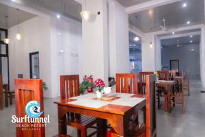 a dining room with a wooden table and chairs at Surftunnel Beach Resort in Weligama