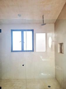 a glass shower in a bathroom with a window at Casita Atardecer in Todos Santos