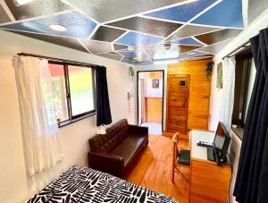 a room with a bed and a couch and a television at Art Bungalow Amami in Amami
