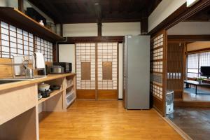a room with a kitchen with wooden floors and a door at 古民家宿torch in Fujikawaguchiko