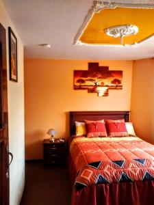 a bedroom with a bed with red pillows on it at Hotel Residencial El Viajero in Tababela