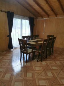a dining room with a wooden table and chairs at Cabañas El Rincón De Huallerupe in Melipeuco