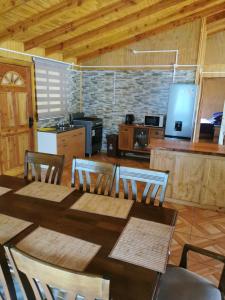 a dining room with a table and chairs and a kitchen at Cabañas El Rincón De Huallerupe in Melipeuco