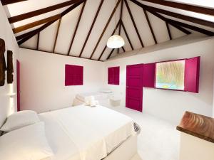 a bedroom with red doors and a white bed at Hotel Coral Sand Islas Del Rosario in Isla Grande