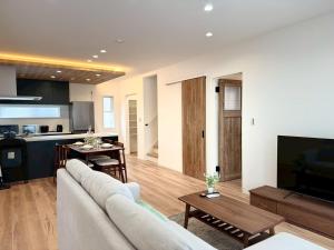 a living room with a couch and a kitchen at Akikawa Koshi 12 プレミアム木造 一棟貸切ヴィラ in Yuge