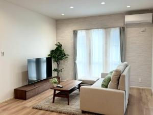 a living room with a couch and a flat screen tv at Akikawa Koshi 12 プレミアム木造 一棟貸切ヴィラ in Yuge