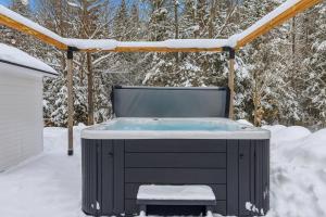 a jacuzzi tub in a snow covered yard at Private Forest Spa Retreat - Modern Chalet in Chertsey