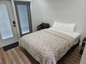 a bedroom with a bed and two windows at Stylish Cabin Escape w - Kitchenette & Ensuite Bath in Port Renfrew
