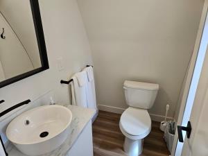 a white bathroom with a sink and a toilet at Stylish Cabin Escape w - Kitchenette & Ensuite Bath in Port Renfrew