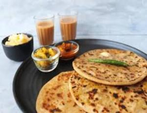 a plate of food with two pizzas and some drinks at Awadh Royal's Hotel in Ayodhya