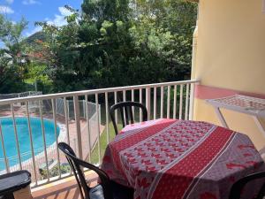 a table and chairs on a balcony next to a pool at APPARTEMENT LOTUS avec PISCINE et à 3 min de la PLAGE Pointe Marin in Sainte-Anne
